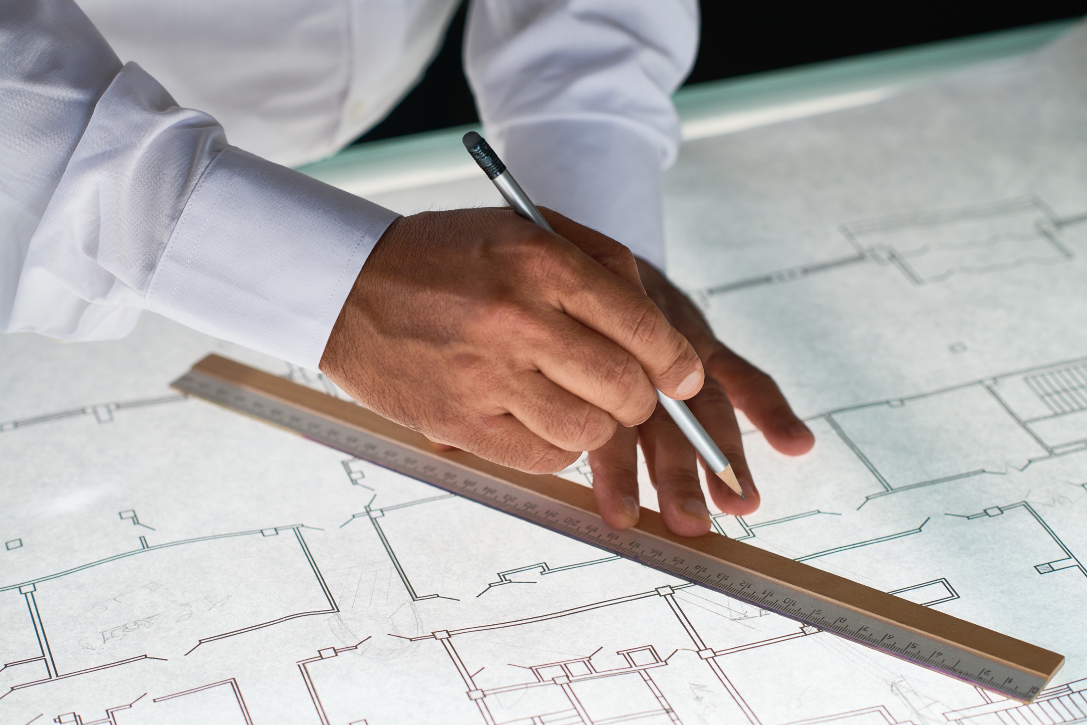 A hand drawing on architectural plans with a scale ruler.